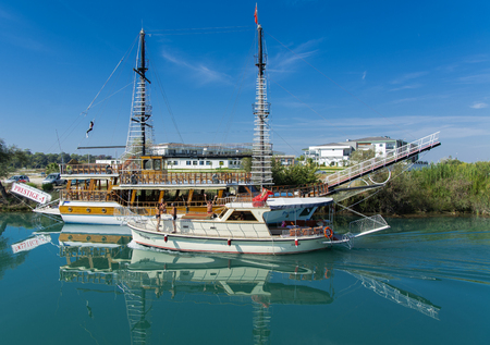 Alanya, Turkey - October 05, 2018. A small sailing ship in a pirate style runs along the coast against a blue sky. Photos of the ship from the sea. The concept of summer holidays, sports, tourismのeditorial素材