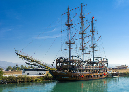 Alanya, Turkey - October 05, 2018. A small sailing ship in a pirate style runs along the coast against a blue sky. Photos of the ship from the sea. The concept of summer holidays, sports, tourismのeditorial素材