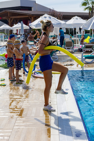 Alanya, Turkey - October 05, 2018. Aqua aerobics instructor conducts classes in the blue clear water of the Kirman Sidera Luxury hotel pool. Fitness concept, summer vacation, sport, tourismのeditorial素材