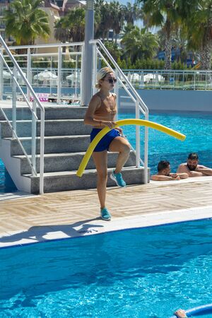 Alanya, Turkey - October 05, 2018. Aqua aerobics instructor conducts classes in the blue clear water of the Kirman Sidera Luxury hotel pool. Fitness concept, summer vacation, sport, tourismのeditorial素材