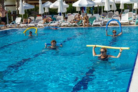 Alanya, Turkey - October 05, 2018. A group of people is engaged in aqua aerobics in the blue clear water of the pool at Kirman Sidera Luxury Spa. Fitness concept, summer vacation, sport, tourismのeditorial素材