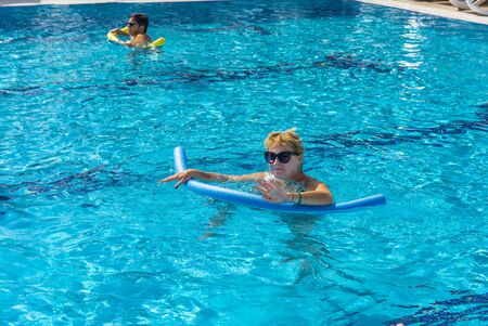 Alanya, Turkey - October 05, 2018. A group of people is engaged in aqua aerobics in the blue clear water of the pool at Kirman Sidera Luxury Spa. Fitness concept, summer vacation, sport, tourismのeditorial素材