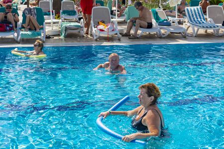 Alanya, Turkey - October 05, 2018. A group of people is engaged in aqua aerobics in the blue clear...