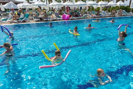 Alanya, Turkey - October 05, 2018. A group of people is engaged in aqua aerobics in the blue clear water of the pool at Kirman Sidera Luxury Spa. Fitness concept, summer vacation, sport, tourismのeditorial素材