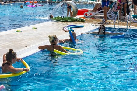 Alanya, Turkey - October 05, 2018. A group of people is engaged in aqua aerobics in the blue clear water of the pool at Kirman Sidera Luxury Spa. Fitness concept, summer vacation, sport, tourismのeditorial素材