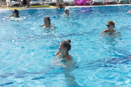 Alanya, Turkey - October 05, 2018. A group of people is engaged in aqua aerobics in the blue clear water of the pool at Kirman Sidera Luxury Spa. Fitness concept, summer vacation, sport, tourismのeditorial素材