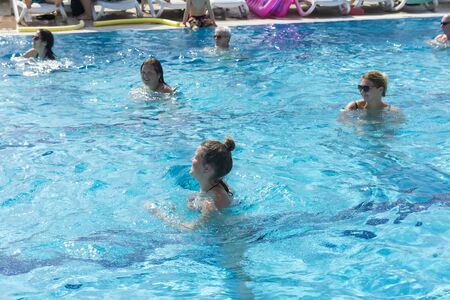 Alanya, Turkey - October 05, 2018. A group of people is engaged in aqua aerobics in the blue clear water of the pool at Kirman Sidera Luxury Spa. Fitness concept, summer vacation, sport, tourismのeditorial素材