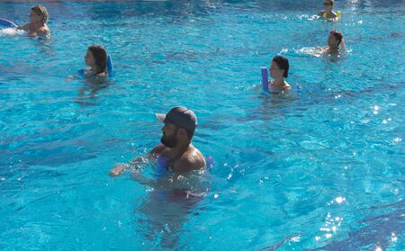 Alanya, Turkey - October 05, 2018. A group of people is engaged in aqua aerobics in the blue clear water of the pool at Kirman Sidera Luxury Spa. Fitness concept, summer vacation, sport, tourismのeditorial素材