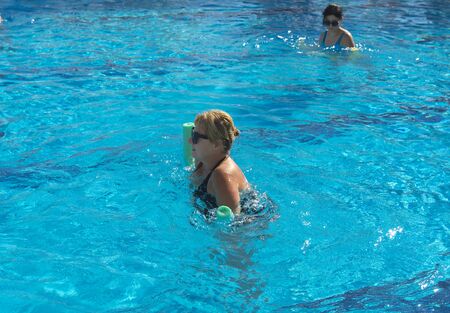 Alanya, Turkey - October 05, 2018. A group of people is engaged in aqua aerobics in the blue clear water of the pool at Kirman Sidera Luxury Spa. Fitness concept, summer vacation, sport, tourismのeditorial素材
