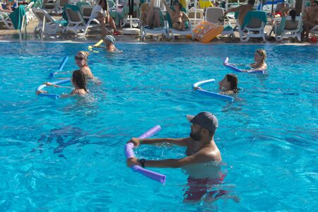 Alanya, Turkey - October 05, 2018. A group of people is engaged in aqua aerobics in the blue clear water of the pool at Kirman Sidera Luxury Spa. Fitness concept, summer vacation, sport, tourismのeditorial素材