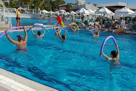 Alanya, Turkey - October 05, 2018. A group of people is engaged in aqua aerobics in the blue clear water of the pool at Kirman Sidera Luxury Spa. Fitness concept, summer vacation, sport, tourismのeditorial素材