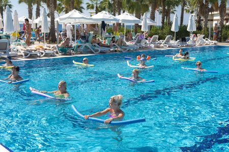 Alanya, Turkey - October 05, 2018. A group of people is engaged in aqua aerobics in the blue clear water of the pool at Kirman Sidera Luxury Spa. Fitness concept, summer vacation, sport, tourismのeditorial素材