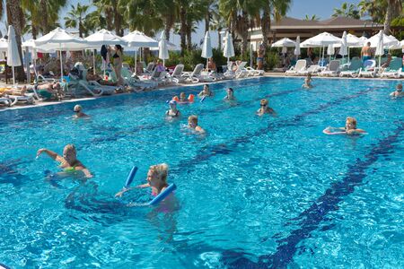 Alanya, Turkey - October 05, 2018. A group of people is engaged in aqua aerobics in the blue clear water of the pool at Kirman Sidera Luxury Spa. Fitness concept, summer vacation, sport, tourismのeditorial素材
