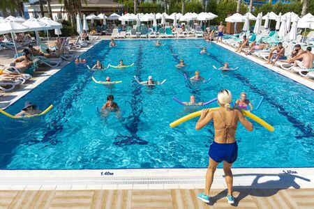 Alanya, Turkey - October 05, 2018. A group of people is engaged in aqua aerobics in the blue clear water of the pool at Kirman Sidera Luxury Spa. Fitness concept, summer vacation, sport, tourismのeditorial素材