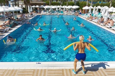 Alanya, Turkey - October 05, 2018. A group of people is engaged in aqua aerobics in the blue clear water of the pool at Kirman Sidera Luxury Spa. Fitness concept, summer vacation, sport, tourismのeditorial素材