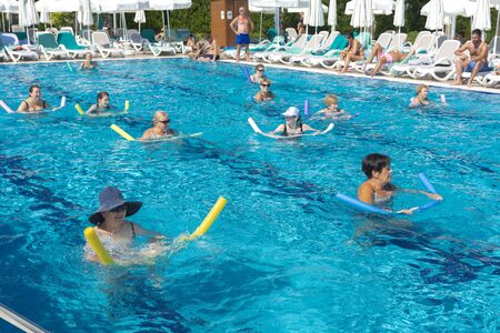 Alanya, Turkey - October 05, 2018. A group of people is engaged in aqua aerobics in the blue clear water of the pool at Kirman Sidera Luxury Spa. Fitness concept, summer vacation, sport, tourismのeditorial素材