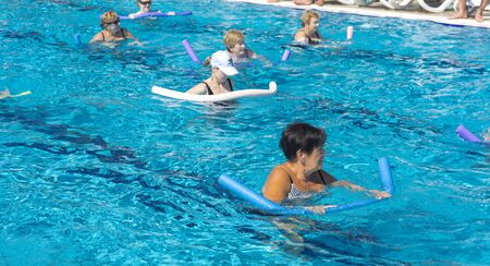 Alanya, Turkey - October 05, 2018. A group of people is engaged in aqua aerobics in the blue clear water of the pool at Kirman Sidera Luxury Spa. Fitness concept, summer vacation, sport, tourismのeditorial素材