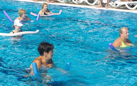 Alanya, Turkey - October 05, 2018. A group of people is engaged in aqua aerobics in the blue clear water of the pool at Kirman Sidera Luxury Spa. Fitness concept, summer vacation, sport, tourismのeditorial素材