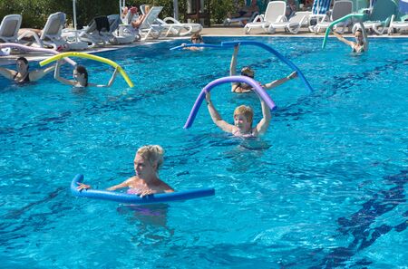 Alanya, Turkey - October 05, 2018. A group of people is engaged in aqua aerobics in the blue clear water of the pool at Kirman Sidera Luxury Spa. Fitness concept, summer vacation, sport, tourismのeditorial素材