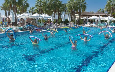Alanya, Turkey - October 05, 2018. A group of people is engaged in aqua aerobics in the blue clear water of the pool at Kirman Sidera Luxury Spa. Fitness concept, summer vacation, sport, tourismのeditorial素材