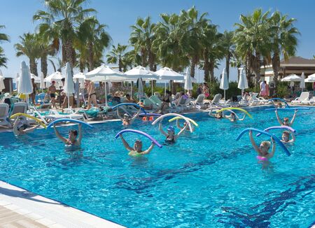 Alanya, Turkey - October 05, 2018. A group of people is engaged in aqua aerobics in the blue clear water of the pool at Kirman Sidera Luxury Spa. Fitness concept, summer vacation, sport, tourismのeditorial素材