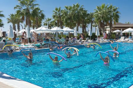 Alanya, Turkey - October 05, 2018. A group of people is engaged in aqua aerobics in the blue clear water of the pool at Kirman Sidera Luxury Spa. Fitness concept, summer vacation, sport, tourismのeditorial素材
