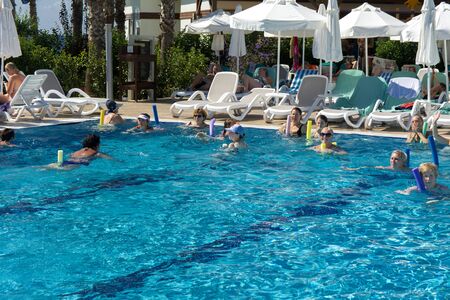 Alanya, Turkey - October 05, 2018. A group of people is engaged in aqua aerobics in the blue clear water of the pool at Kirman Sidera Luxury Spa. Fitness concept, summer vacation, sport, tourismのeditorial素材