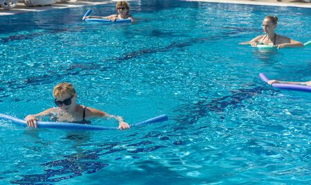 Alanya, Turkey - October 05, 2018. A group of people is engaged in aqua aerobics in the blue clear water of the pool at Kirman Sidera Luxury Spa. Fitness concept, summer vacation, sport, tourismのeditorial素材
