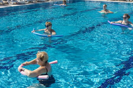 Alanya, Turkey - October 05, 2018. A group of people is engaged in aqua aerobics in the blue clear water of the pool at Kirman Sidera Luxury Spa. Fitness concept, summer vacation, sport, tourismのeditorial素材