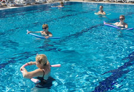 Alanya, Turkey - October 05, 2018. A group of people is engaged in aqua aerobics in the blue clear water of the pool at Kirman Sidera Luxury Spa. Fitness concept, summer vacation, sport, tourismのeditorial素材