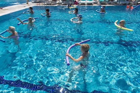 Alanya, Turkey - October 05, 2018. A group of people is engaged in aqua aerobics in the blue clear water of the pool at Kirman Sidera Luxury Spa. Fitness concept, summer vacation, sport, tourismのeditorial素材