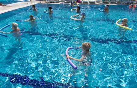 Alanya, Turkey - October 05, 2018. A group of people is engaged in aqua aerobics in the blue clear water of the pool at Kirman Sidera Luxury Spa. Fitness concept, summer vacation, sport, tourismのeditorial素材