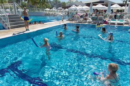 Alanya, Turkey - October 05, 2018. A group of people is engaged in aqua aerobics in the blue clear water of the pool at Kirman Sidera Luxury Spa. Fitness concept, summer vacation, sport, tourismのeditorial素材