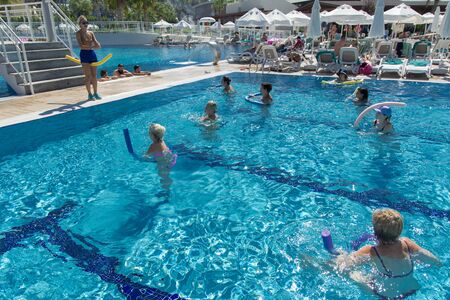 Alanya, Turkey - October 05, 2018. A group of people is engaged in aqua aerobics in the blue clear water of the pool at Kirman Sidera Luxury Spa. Fitness concept, summer vacation, sport, tourismのeditorial素材