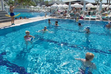 Alanya, Turkey - October 05, 2018. A group of people is engaged in aqua aerobics in the blue clear water of the pool at Kirman Sidera Luxury Spa. Fitness concept, summer vacation, sport, tourismのeditorial素材