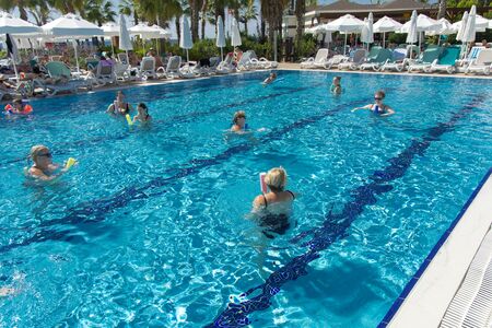 Alanya, Turkey - October 05, 2018. A group of people is engaged in aqua aerobics in the blue clear water of the pool at Kirman Sidera Luxury Spa. Fitness concept, summer vacation, sport, tourismのeditorial素材