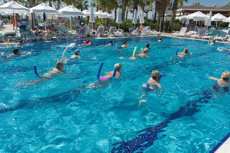 Alanya, Turkey - October 05, 2018. A group of people is engaged in aqua aerobics in the blue clear water of the pool at Kirman Sidera Luxury Spa. Fitness concept, summer vacation, sport, tourismのeditorial素材