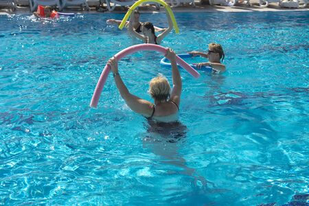 Alanya, Turkey - October 05, 2018. A group of people is engaged in aqua aerobics in the blue clear water of the pool at Kirman Sidera Luxury Spa. Fitness concept, summer vacation, sport, tourismのeditorial素材