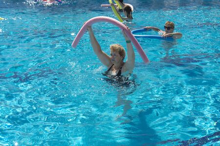 Alanya, Turkey - October 05, 2018. A group of people is engaged in aqua aerobics in the blue clear water of the pool at Kirman Sidera Luxury Spa. Fitness concept, summer vacation, sport, tourismのeditorial素材