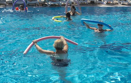 Alanya, Turkey - October 05, 2018. A group of people is engaged in aqua aerobics in the blue clear water of the pool at Kirman Sidera Luxury Spa. Fitness concept, summer vacation, sport, tourismのeditorial素材