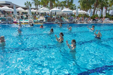 Alanya, Turkey - October 05, 2018. A group of people is engaged in aqua aerobics in the blue clear water of the pool at Kirman Sidera Luxury Spa. Fitness concept, summer vacation, sport, tourismのeditorial素材