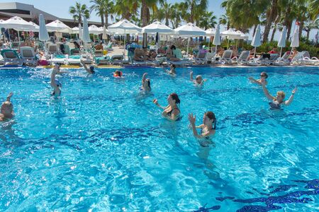 Alanya, Turkey - October 05, 2018. A group of people is engaged in aqua aerobics in the blue clear water of the pool at Kirman Sidera Luxury Spa. Fitness concept, summer vacation, sport, tourismのeditorial素材