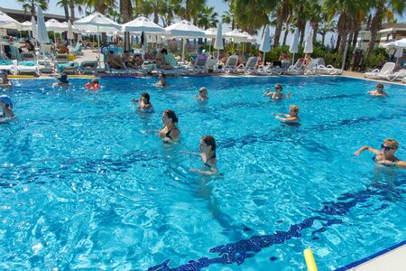 Alanya, Turkey - October 05, 2018. A group of people is engaged in aqua aerobics in the blue clear water of the pool at Kirman Sidera Luxury Spa. Fitness concept, summer vacation, sport, tourismのeditorial素材
