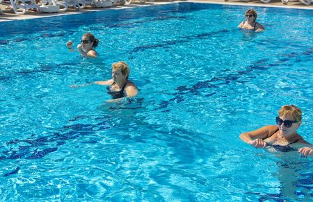 Alanya, Turkey - October 05, 2018. A group of people is engaged in aqua aerobics in the blue clear water of the pool at Kirman Sidera Luxury Spa. Fitness concept, summer vacation, sport, tourismのeditorial素材
