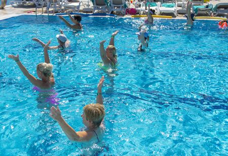 Alanya, Turkey - October 05, 2018. A group of people is engaged in aqua aerobics in the blue clear water of the pool at Kirman Sidera Luxury Spa. Fitness concept, summer vacation, sport, tourismのeditorial素材