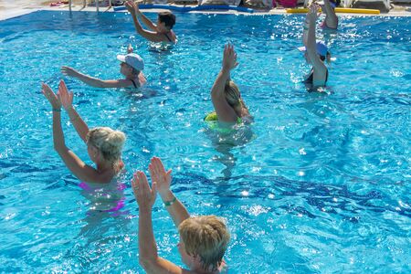 Alanya, Turkey - October 05, 2018. A group of people is engaged in aqua aerobics in the blue clear water of the pool at Kirman Sidera Luxury Spa. Fitness concept, summer vacation, sport, tourismのeditorial素材