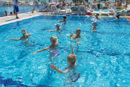 Alanya, Turkey - October 05, 2018. A group of people is engaged in aqua aerobics in the blue clear water of the pool at Kirman Sidera Luxury Spa. Fitness concept, summer vacation, sport, tourismのeditorial素材