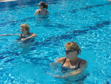 Alanya, Turkey - October 05, 2018. A group of people is engaged in aqua aerobics in the blue clear water of the pool at Kirman Sidera Luxury Spa. Fitness concept, summer vacation, sport, tourismのeditorial素材