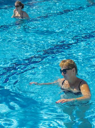 Alanya, Turkey - October 05, 2018. A group of people is engaged in aqua aerobics in the blue clear water of the pool at Kirman Sidera Luxury Spa. Fitness concept, summer vacation, sport, tourismのeditorial素材