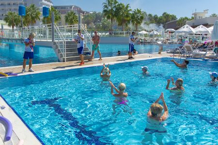 Alanya, Turkey - October 05, 2018. A group of people is engaged in aqua aerobics in the blue clear water of the pool at Kirman Sidera Luxury Spa. Fitness concept, summer vacation, sport, tourismのeditorial素材